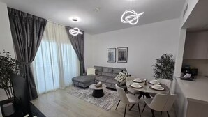 Een moderne woonkamer met een grijze bank, een eettafel gedekt voor vier personen en een salontafel.