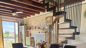 A dining area with a wooden table, black chairs, a vase with flowers, and a staircase with a metal railing. - SG Family - Girasole Apartment (Peschiera del Garda)
