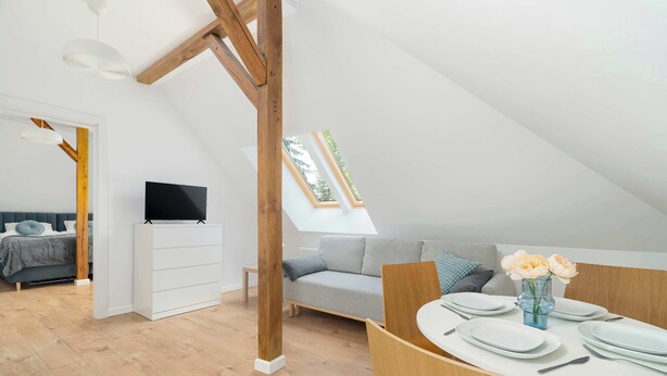 A modern loft bedroom with a lofted sleeping area, a television, and a dining table set for four.