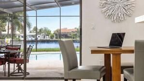 Une chambre avec vue sur un plan d’eau, une piscine et un coin repas comprenant des chaises et une table.