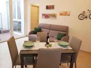 Ein Essbereich mit Tisch für vier Personen, einer Couch und einem Kunstwerk an der Wand.