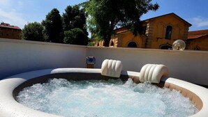 A hot tub with water jets, surrounded by a beige wall and trees. - L&G's Roof Terrace, near the Tower of Pisa. (Pisa)
