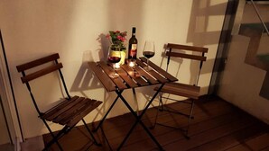 A small wooden table with two chairs, a bottle of wine, a glass, and a candle. - L&G's Roof Terrace, near the Tower of Pisa. (Pisa)