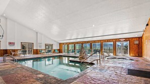 An indoor swimming pool with a stone floor, lounge chairs, and a hot tub. - Mountain Views Indoor Pool & Sauna Fireplace (Gatlinburg)
