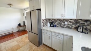 Una cocina moderna con armarios blancos, un refrigerador de acero inoxidable, una cafetera y un tostador.