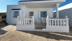 Un bâtiment blanc doté d’un balcon, de deux fenêtres et d’une porte.