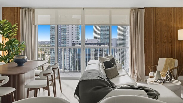 A modern living room with a large window, a sofa, a dining table, and a chair. - Brickell Bayview Balcony Pool  Free Parking (Miami)