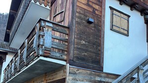 A wooden building with a balcony and a staircase leading to the entrance.