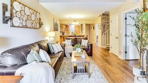 A spacious living room with a leather sofa, a coffee table, and a large abstract wall art piece. - Ski, Hike & Explore: Mtn-view Haven in Gatlinburg! (Gatlinburg)