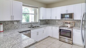A modern kitchen with white cabinets, granite countertops, stainless steel appliances, and a window providing natural light. - Yard w/ Lake View: Remote Working Hub in Homestead (Homestead)