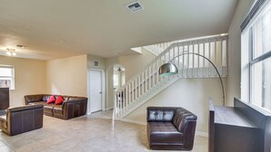 A spacious living area with a staircase, leather sofas, and a large window. - Yard w/ Lake View: Remote Working Hub in Homestead (Homestead)