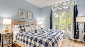 Een slaapkamer met een bed, twee nachtkastjes, een raam met gordijnen en wanddecoratie.
