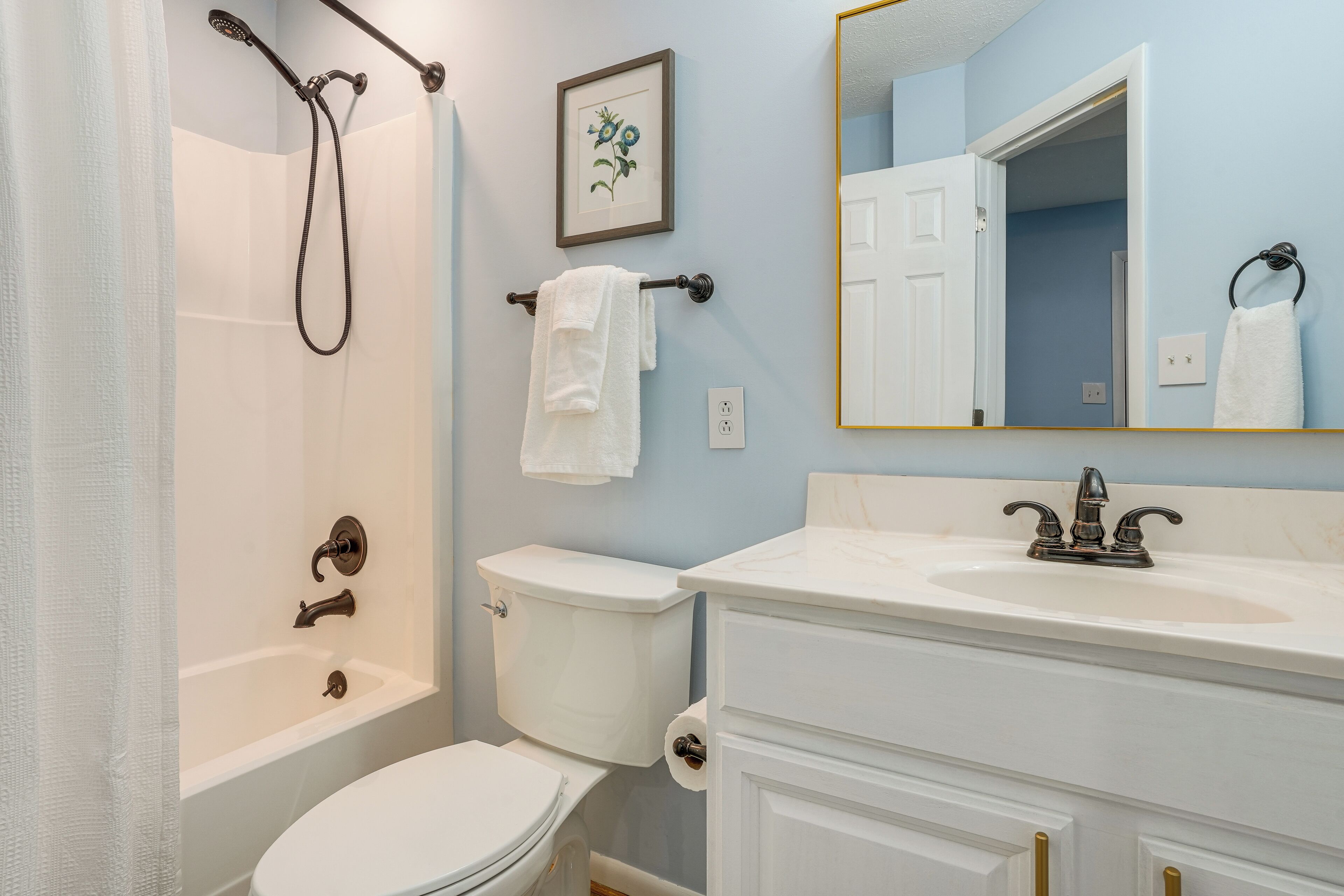 Un baño con bañera, inodoro, lavabo y espejo.