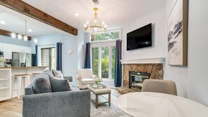 Een moderne woonkamer met een open haard, een eettafel en een keuken op de achtergrond.