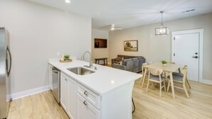 Una cocina moderna con armarios blancos, lavavajillas y un comedor con mesa y sillas.