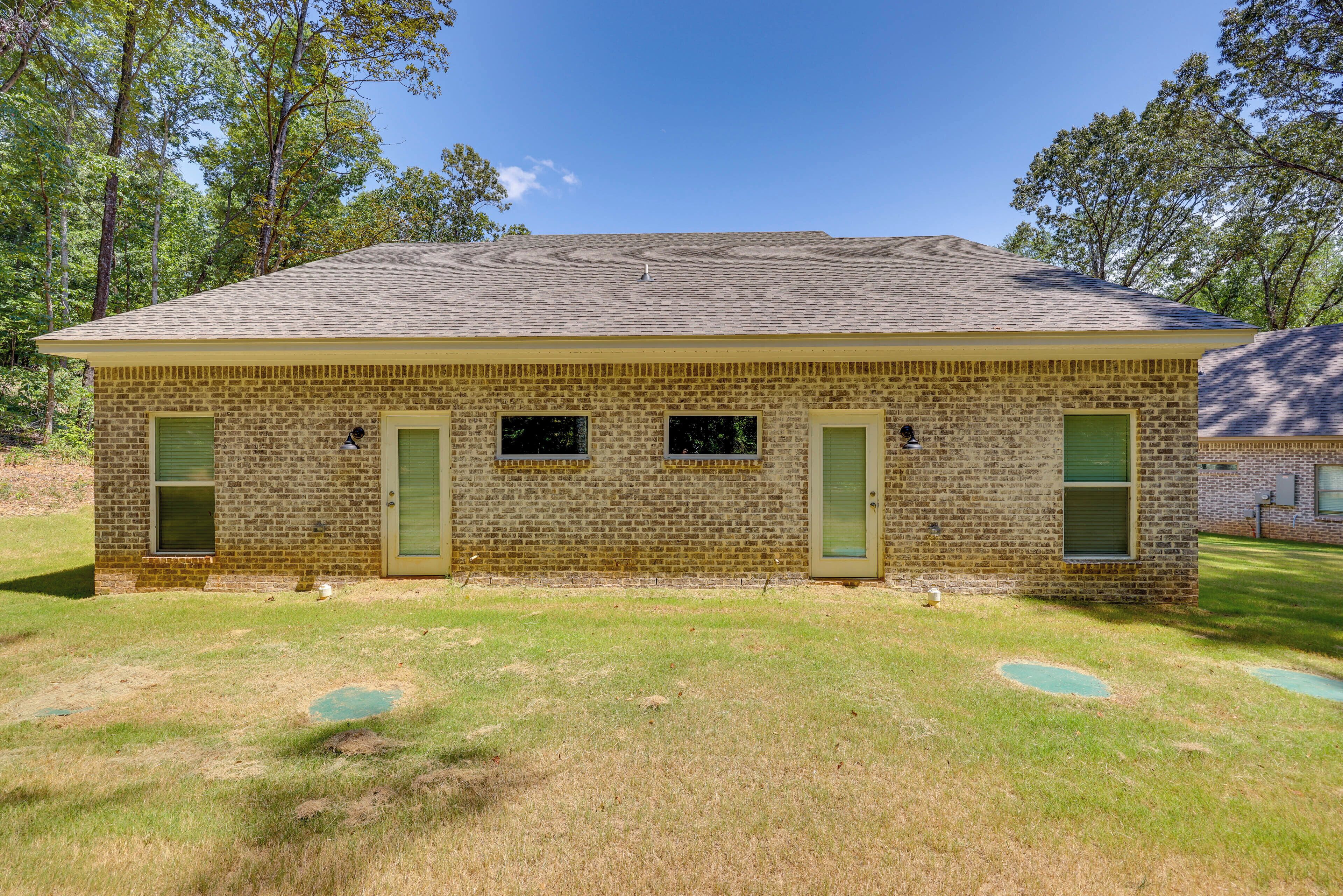 A single-story brick building with a flat roof, two green doors, and three windows.