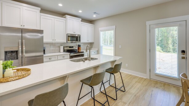 A modern kitchen with white cabinets, stainless steel appliances, and a large island with bar stools. - Near 17 Springs Sports Complex: Millbrook Duplex! (Millbrook)