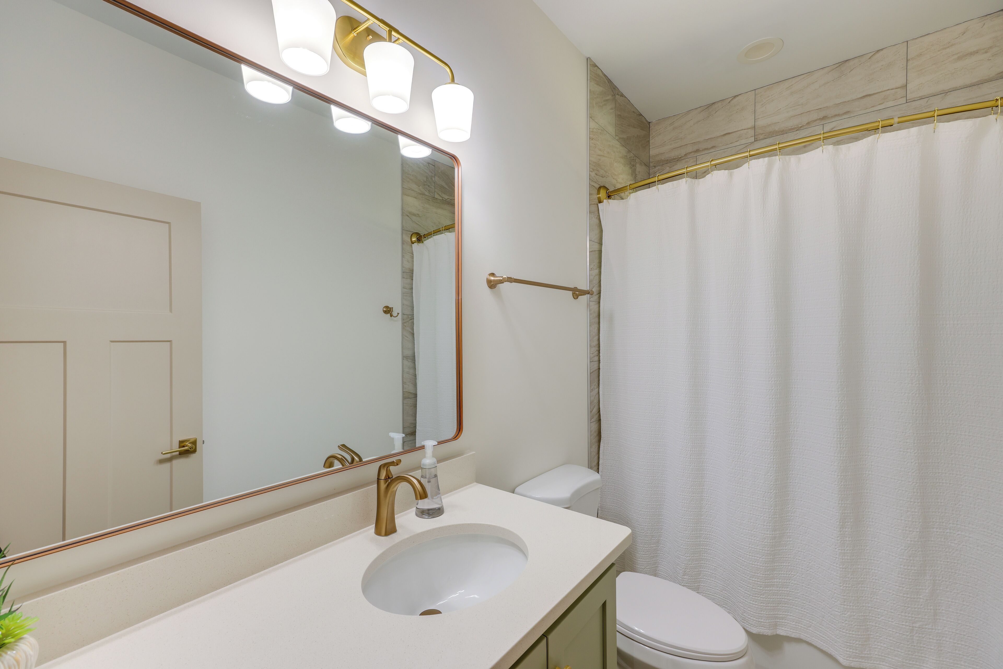 Ein Badezimmer mit weißem Waschbecken, einem Spiegel, einer Toilette und einer Duschvorhang.