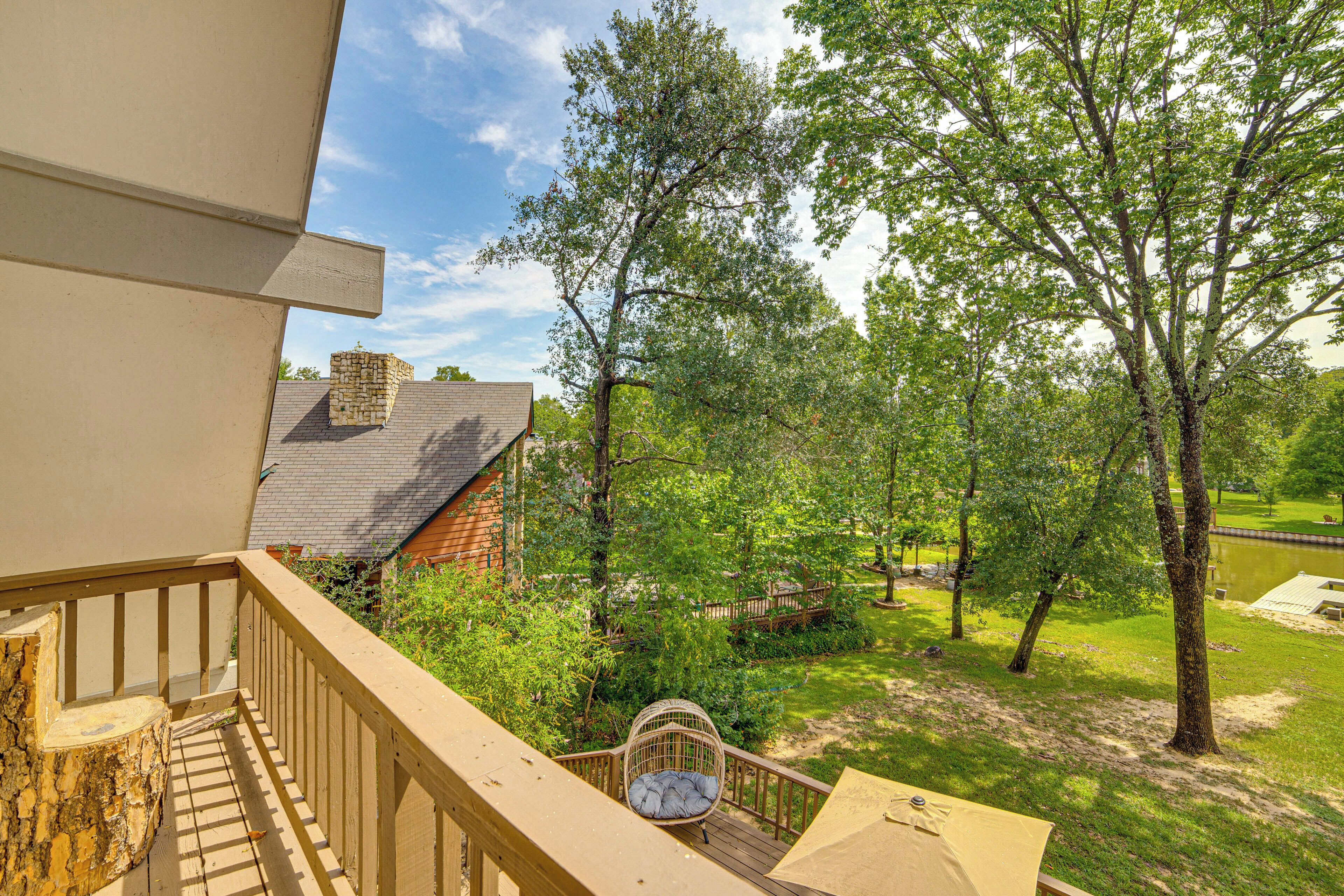 Ein Balkon mit Blick auf einen Garten, eine Holzterrasse und eine Steinmauer.
