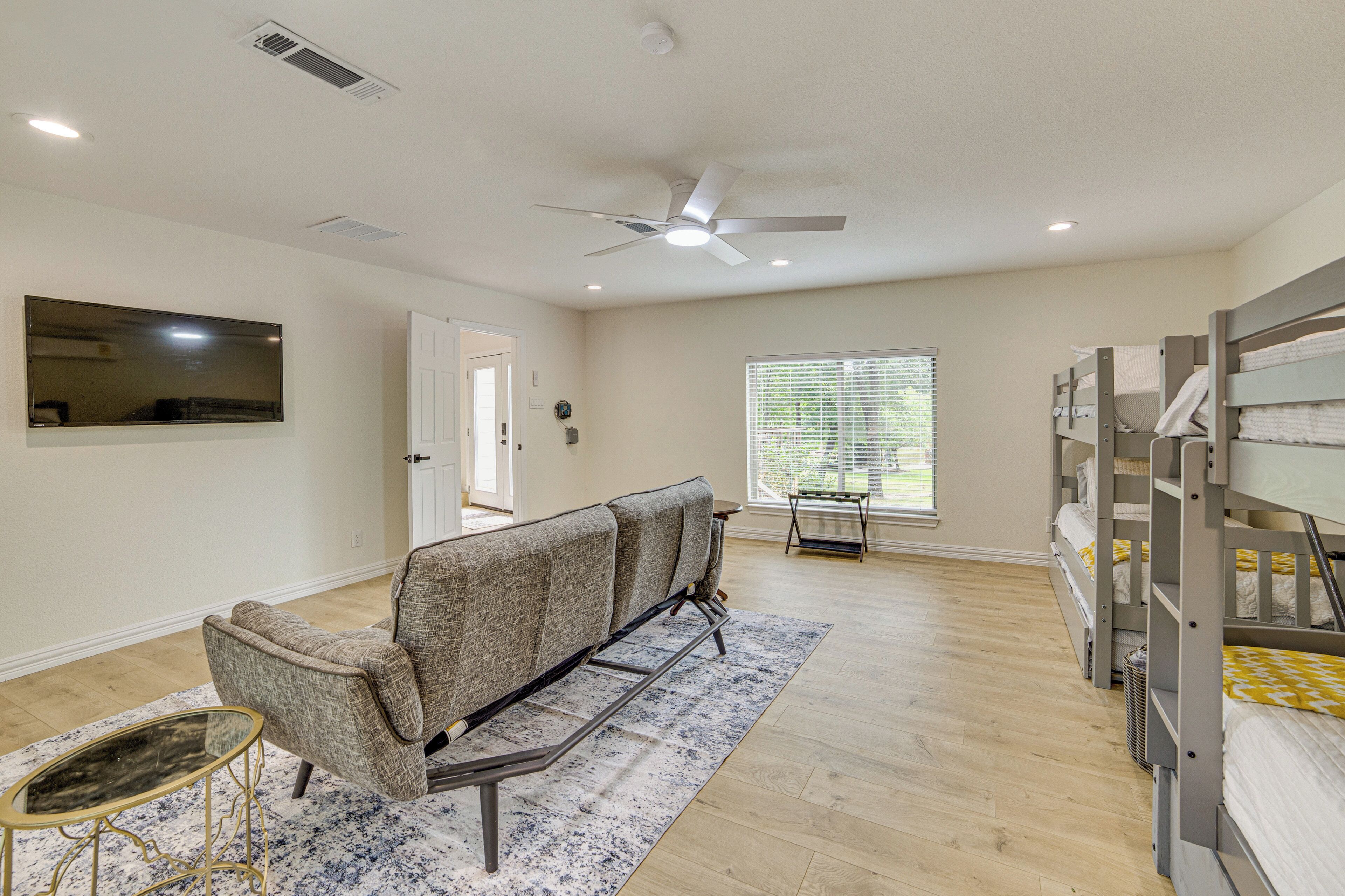 A spacious room with a ceiling fan, bunk beds, a sofa, and a TV.