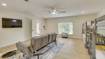 A spacious room with a ceiling fan, bunk beds, a sofa, and a TV.