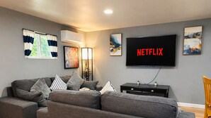 Un soggiorno moderno con un divano componibile, una televisione a schermo piatto e opere d'arte alle pareti.