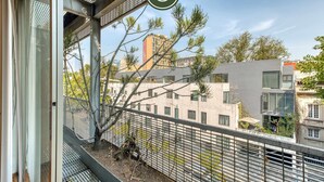 Ein Balkon mit Metallgeländer, Blick auf Gebäude und einen Baum.