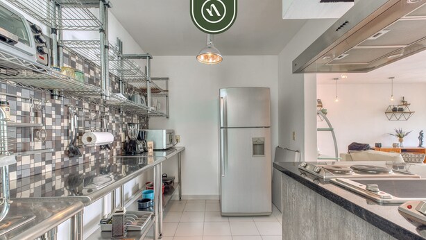 Eine moderne Küche mit Edelstahlgeräten, einer gefliesten Spritzschutzwand und einer zentralen Kochinsel.