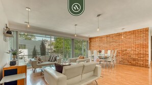 Ein modernes Wohnzimmer mit einem weißen Sofa, einem Esstisch mit Stühlen und einer Ziegelwand.