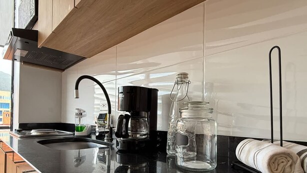 Una cocina moderna con encimera negra, electrodomésticos de acero inoxidable y un amplio ventanal que proporciona luz natural.