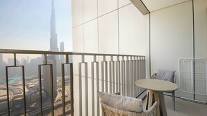 A balcony with a view of a city skyline, a wicker chair with cushions, a small table, and a white radiator. - Silk Valley - Luxury 2B near Dubai Mall (Dubai)
