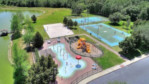 Un parque con cancha de baloncesto, parque infantil y un lago.