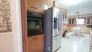 Een keuken met houten kastjes, een roestvrijstalen koelkast en een oven.