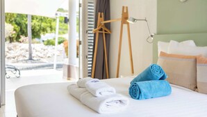 Ein Hotelzimmer mit Bett, Handtüchern, einem Bild an der Wand und Blick ins Freie.