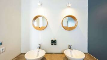 A bathroom with two sinks, two round mirrors, and two wall-mounted light fixtures.