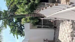 Un bâtiment à deux étages, à la façade blanche, doté d’une fenêtre en bois et d’un balcon carrelé.