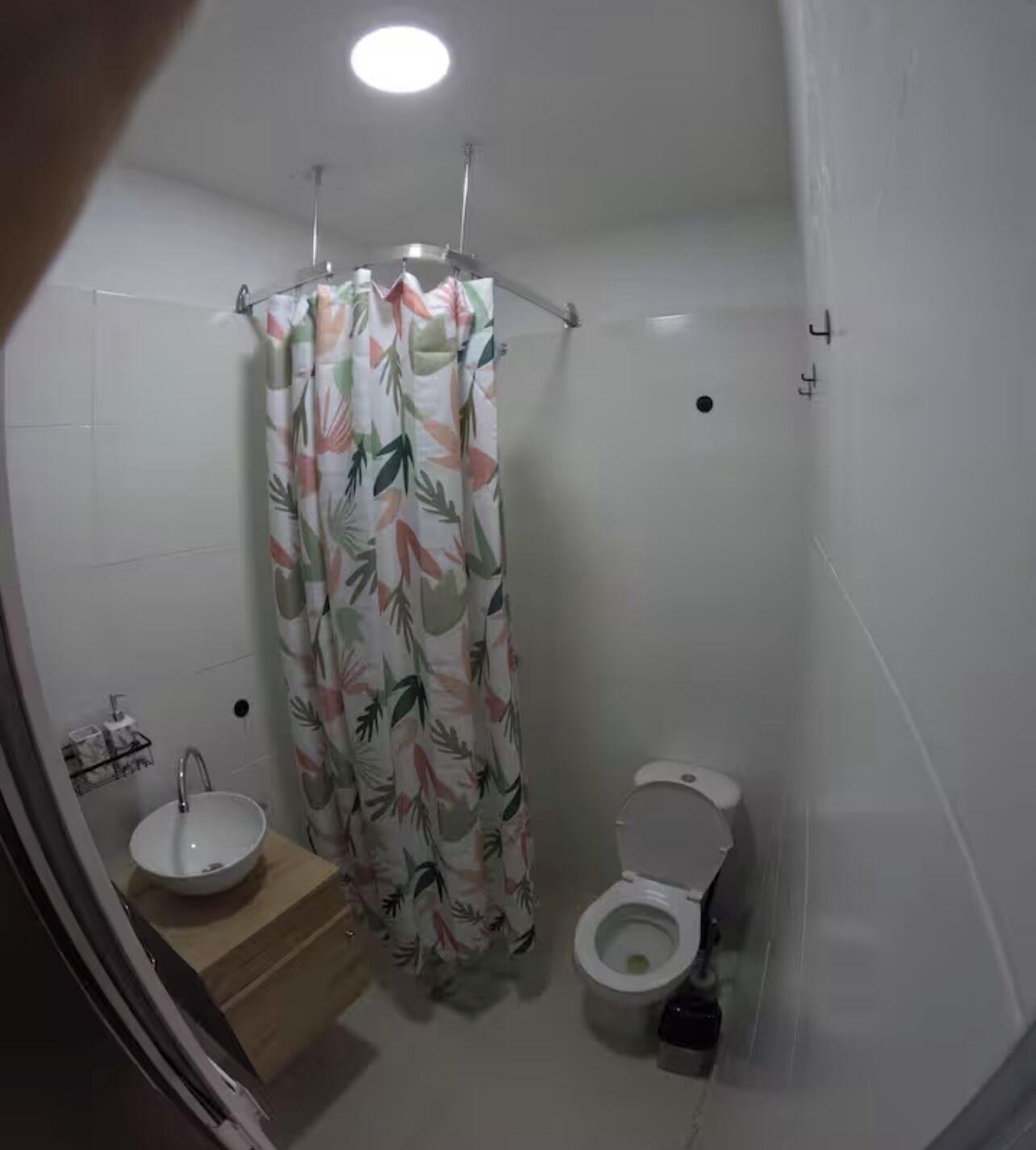 Een badkamer met douchegordijn, wastafel en toilet.