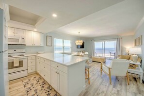 Una cocina moderna con armarios blancos, una isla central y un comedor con vistas.