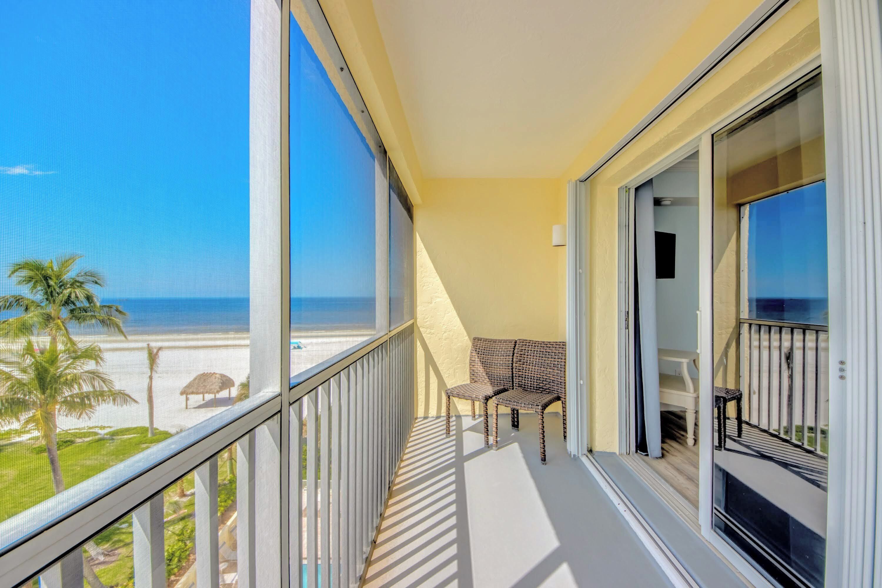Un balcon avec vue sur la plage, une chaise et une table.