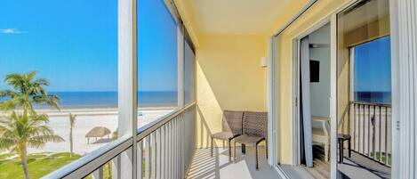 Un balcon avec vue sur la plage, une chaise et une table.