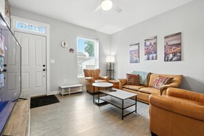 Un salon moderne avec un canapé, des fauteuils, une table basse et un téléviseur.