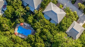 Vista aérea de una zona residencial con varias casas, una piscina y abundante vegetación.