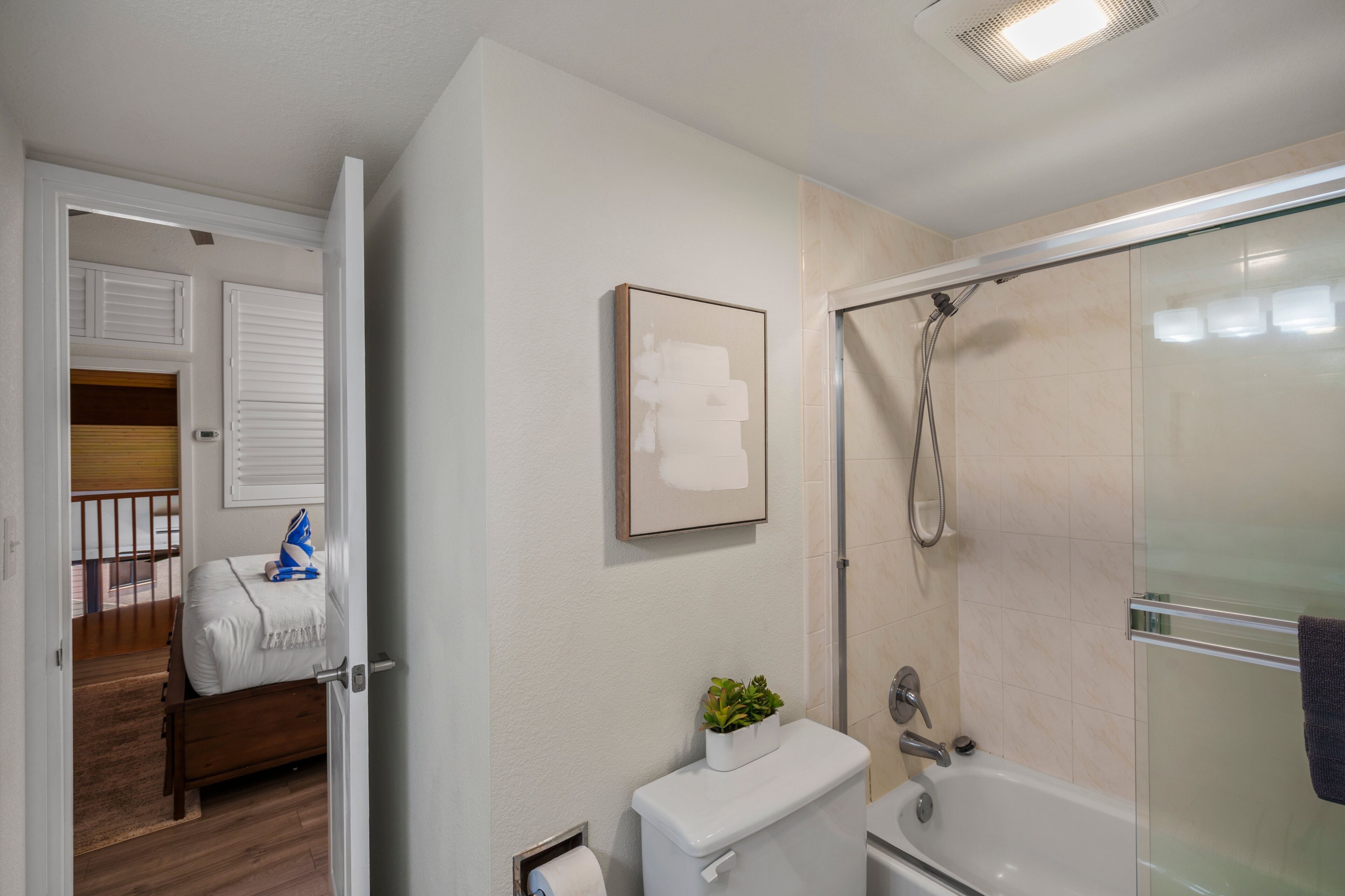 A bathroom with a toilet, a shower, and a glass-enclosed shower stall.