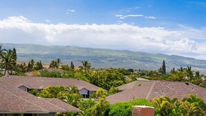A residential area with houses, lush greenery, and a mountainous backdrop under a clear sky. - Kamaole Sands #5-401 2 Bedroom Condo (Kihei)