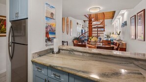 A modern kitchen with a marble countertop, blue cabinets, and a built-in refrigerator. - Kamaole Sands #5-401 2 Bedroom Condo (Kihei)