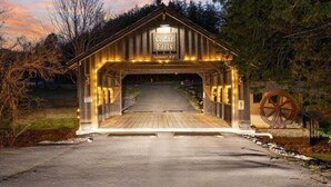 Un puente cubierto de madera con un cartel que dice "Cedar Falls" y una rueda grande en la entrada.