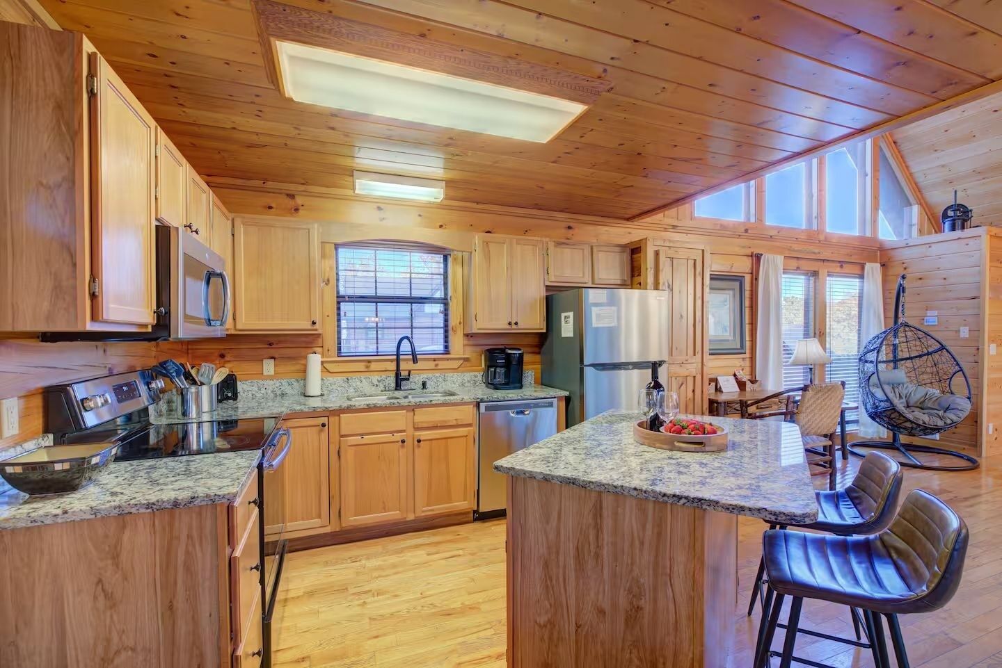 A spacious kitchen with wooden cabinets, granite countertops, and a central island with seating.