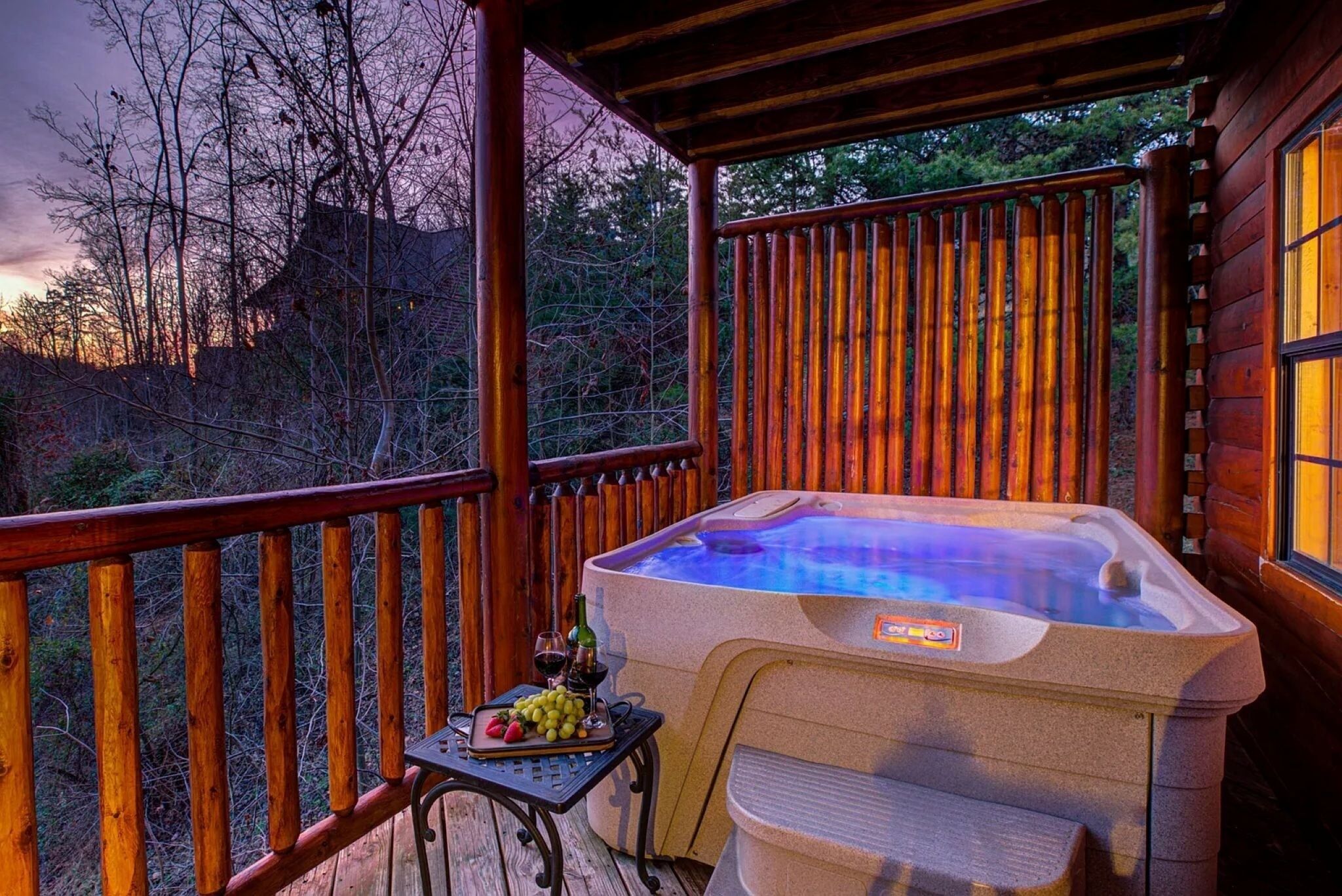 A hot tub on a wooden deck with a table and drinks.