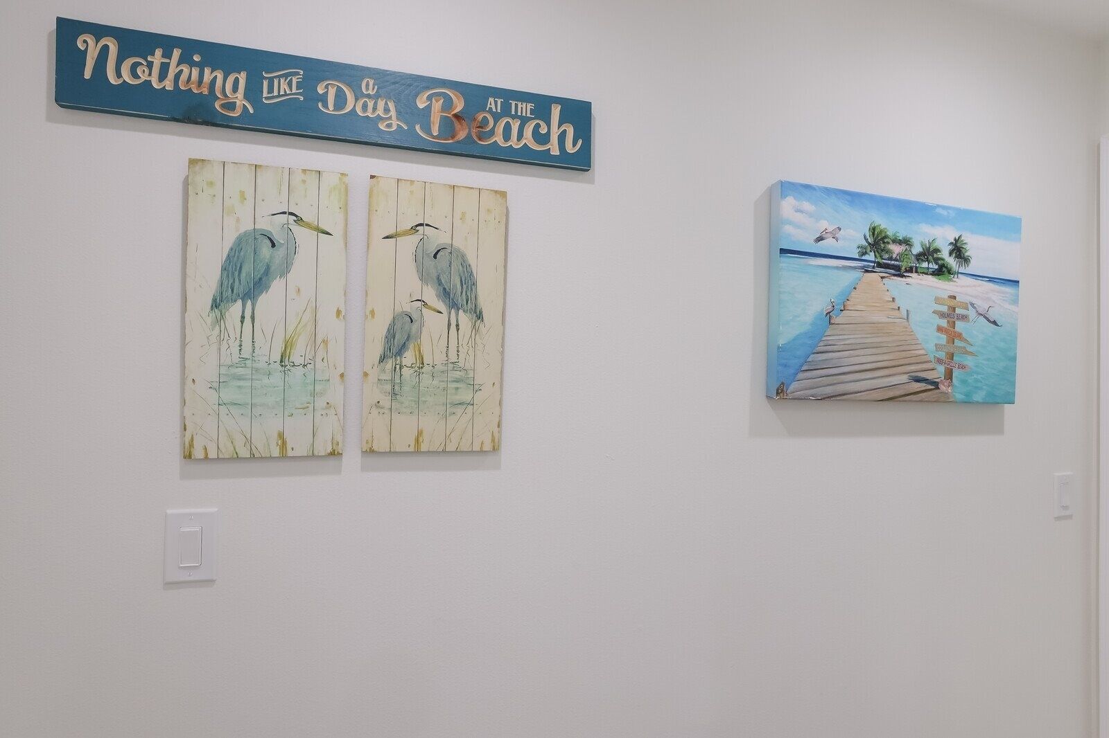 Two wall-mounted artworks depicting birds and a beach scene.