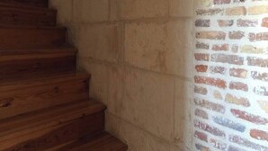 A staircase with wooden steps leading up to a brick wall. - Studio Mezzanine place du marché (La Rochelle)